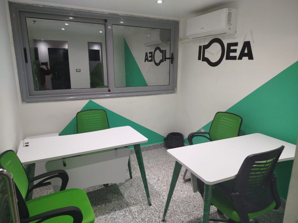 a room with white tables and green chairs