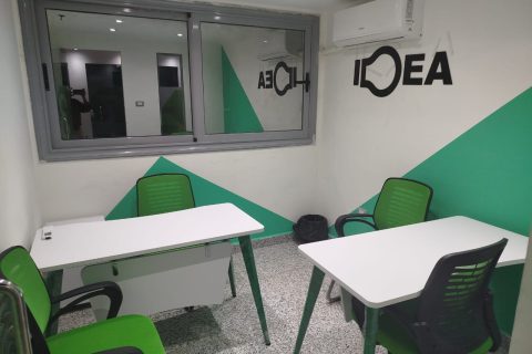 a room with white tables and green chairs